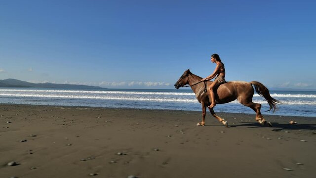 Sexy woman on a galloping horse on the beach slow motion waves breaking in background Costa Rica