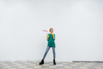 A young girl poses with a roller in front of a white wall. Repair of the interior.