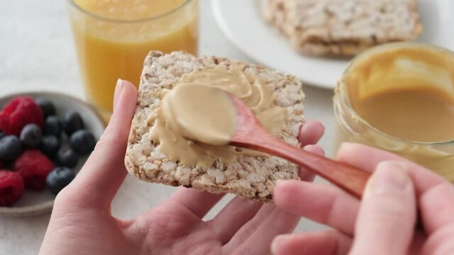 Rice crispbread with peanut butter and banana. Time lapse female hands preparing healthy vegan vegetarian diet toast with crispbread, nut butter and banana