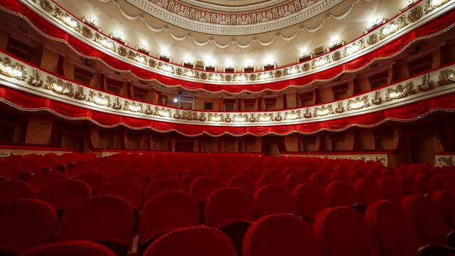 Classical theater inside. Rows of empty red velvet chairs in the opera house. Beautiful dramatic hall with vacant seats.