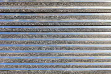 texture of steel strips parallel to each other alternating with gray granite