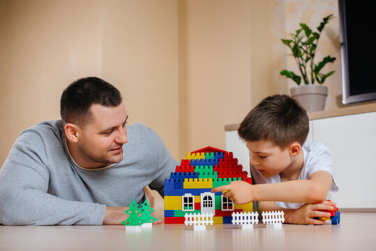 A little boy together with his father is played by a constructor and builds a house. Construction of a family home.