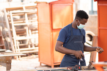 african carpenter wearing a face mask at work