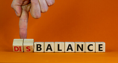 Balance or disbalance symbol. Businessman turns cubes and changes the word disbalance to balance. Beautiful orange background, copy space. Business, balance or disbalance concept.