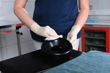 Preparation of the surgical office for the operation. An employee of the dental clinic wipes the headrest at the couch . Disinfection of equipment. An unrecognizable person.