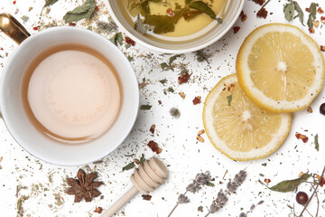 Herbal tea, top view. Dry herbs, lemon slices and tea cups on white. Herbs in bulk, zero waste and...