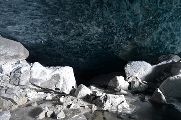 Glacier grotto with blue clear glacier ice and stones