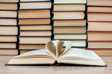 Open book, heart made from book sheets.Solid books on a wooden table. Education. 