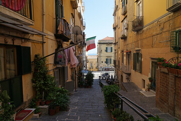 Fototapeta na wymiar Naples steep narrow street with balconies with fresh linen and Italian flag, traditional living in Naples, Italy