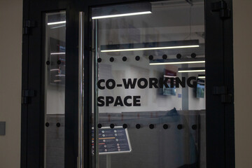 inscription on the transparent door "coworking space". a place for collaboration and freelancing. Black door and black lettering. Style office. 