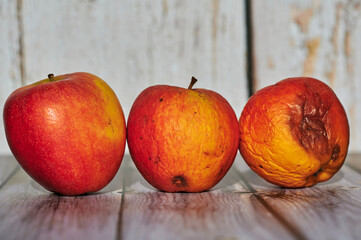 Apples lit from the sun decoratively lying on a wooden underground.