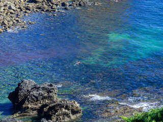 Paisaje minimalista de un bañista en medio del mar azul y verde esmeralda en Pendueles , costa de Asturias en España, verano 2020.


