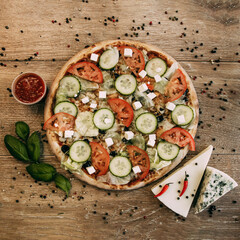 Vegetable pizza with mozzarella, fresh tomatoes and cucumber. Green basil leaves. Two types of blue cheese