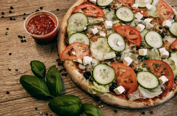 Vegetable pizza with mozzarella, fresh tomatoes and cucumber. Green basil leaves