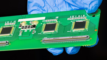 Detail of green printed circuit board in engineer hand isolated on a black background. Close-up of...