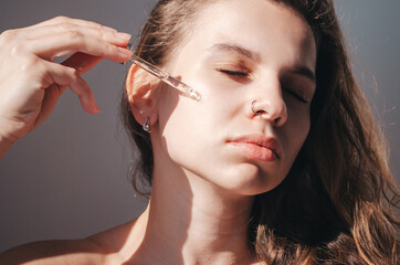 Obraz premium young beautiful woman uses serum for face. The concept of facial skin care.