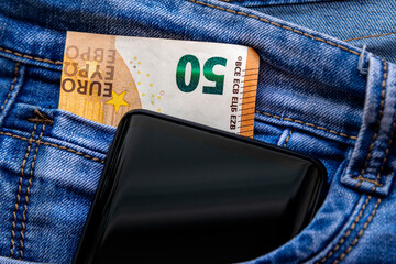 Fifty euro banknote and smartphone in blue jeans pocket. Money for travel and shopping