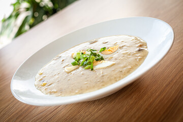 Cooked food in a restaurant on a white plate - dill soup with egg .