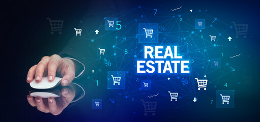 hand holding wireless peripheral with REAL ESTATE inscription, online shopping concept