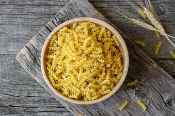 Raw auger pasta in bowl or spoon, uncooked fusilli with wheat