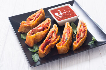 Pizza roll stromboli with cheese salami olives and tomatoes