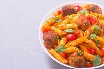 Italian penne pasta with meatballs and tomatoes