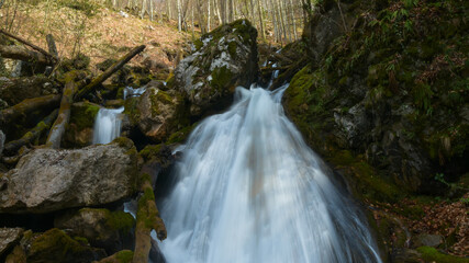 A huge debit waterfall flowing through large mossy stones and boulders. Spring season, Sureanu Mountains, Carpathia, Romania