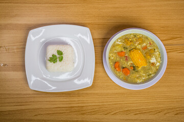 plato de sopa de primera vista con pollo, huevo y maíz en el centro, acompañado de arroz a un lado, concepto de vida saludable en casa