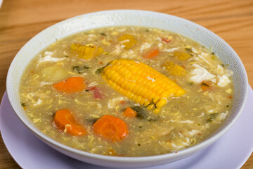 closed view bowl of seasoned soup with shredded chicken, egg and corn in the center, healthy living concept at home