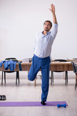 Young male employee doing sport exercises during break