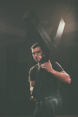 Young man carrying a wooden cross.