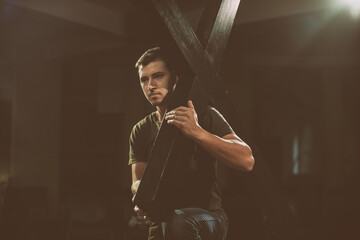 Young man carrying a wooden cross.