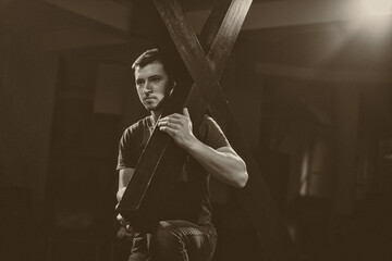 Young man carrying a wooden cross.