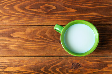 Green cup of milk on a vintage wooden background. Flat top view. Green mug with milk.
