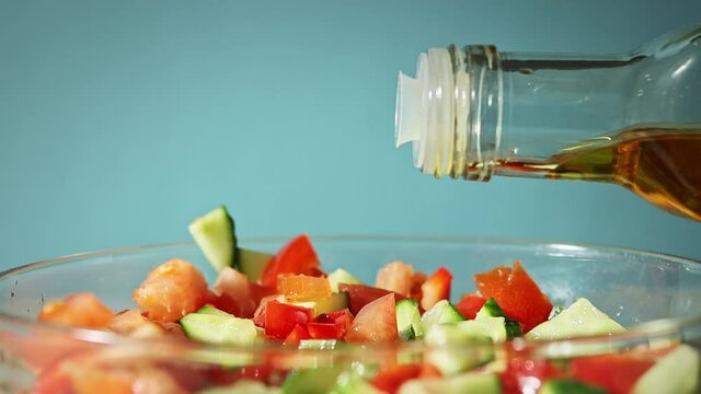 olive oil pouring into bowl mixed vegetable salad with cucumber tomato and red peper 