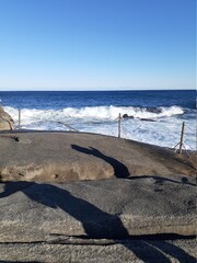 The sea behind the wooden fence and rocks.