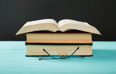 Open book on a stack of books on a table.