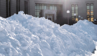 Huge snowdrifts under bright winter sun near the entrance to a library with a message of entrance in Russian