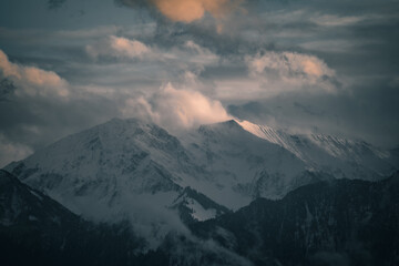 swiss mountains during sunset with fog and clouds and snowy mountains in the alps