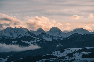 swiss mountains during sunset with fog and clouds and snowy mountains in the alps