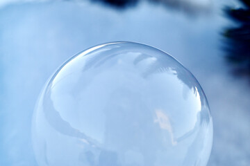 Freezing soap bubble on the snow in the shade of a Christmas tree