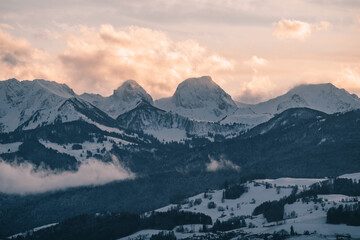 swiss mountains during sunset with fog and clouds and snowy mountains in the alps