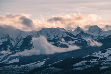 Obraz na płótnie Canvas swiss mountains during sunset with fog and clouds and snowy mountains in the alps