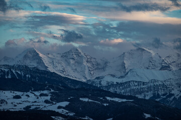 swiss mountains during sunset with fog and clouds and snowy mountains in the alps