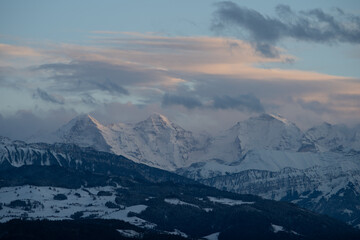 Naklejka na ściany i meble swiss mountains during sunset with fog and clouds and snowy mountains in the alps