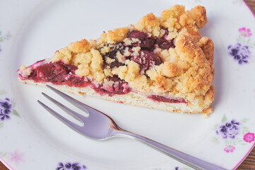 cherry crumble cake on a plate, beside is lying a fork