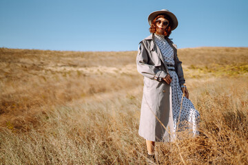 Stylish woman in coat and hat enjoys nature. Spring fashion. People, freedom, lifestyle, travel and vacations concept.