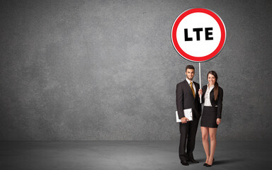 Young business person holdig traffic sign with LTE abbreviation, technology solution concept