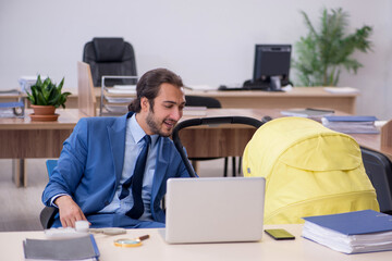 Young male employee looking after new born at workplace