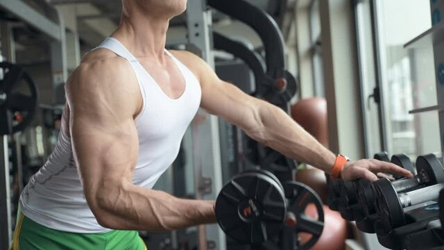 fit man training biceps muscles at gym.